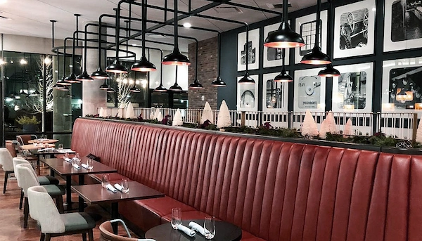 Mesas de restaurante con cubiertos puestos sobre ellas.